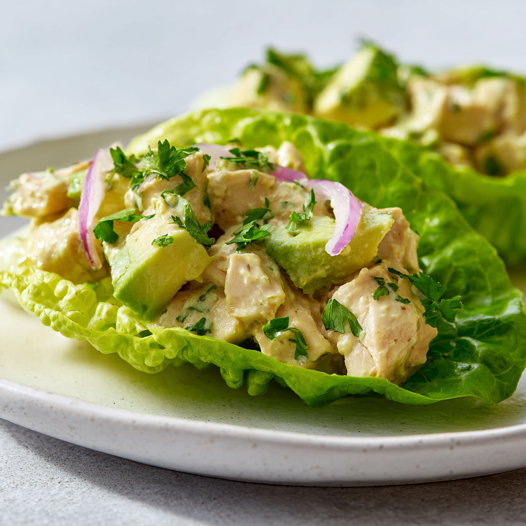 Une salade de laitue et de poulet avec des légumes verts et des herbes.