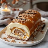 Une bûche glacée à la vanille, recouverte de caramel et de morceaux de biscuit, présentée sur une assiette.