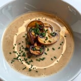 Une soupe crémeuse aux champignons garnie de brins de ciboulette.