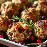 Des boules de stuffing dorées, garnies de canneberges et d'herbes, présentées sur un plat.