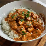 Un plat de poulet à la sauce crémeuse servi sur un lit de riz blanc, garni de persil frais.