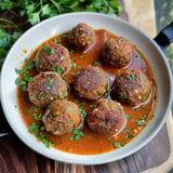 Des boulettes de viande garnies de coriandre dans une sauce épicée.