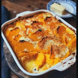 Un plat de gratin de courge d'hiver doré et croustillant, servi avec un morceau de beurre à côté.