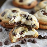 Des biscuits aux pépites de chocolat avec une garniture crémeuse, coupés en deux pour révéler leur intérieur moelleux.