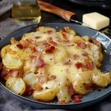 Un plat de pommes de terre garnies de fromage fondu et de lardons croustillants, servi dans une assiette grise.