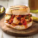 Un sandwich de poisson avec des légumes grillés et une sauce tomate.