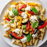 Une salade de pâtes aux légumes grillés et ricotta, servie sur un plateau.
