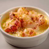 Une casserole de langoustines flambée au cognac dans un bol.