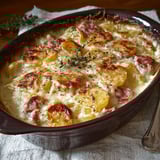 Une gratin de pommes de terre à la saucisse de Morteau et à la cancoillotte est servie sur un plateau.