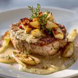 Un filet mignon de porc aux pommes est servie sur un plateau avec une sauce.