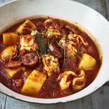 Un plat de calamars au chorizo dans un bol blanc.