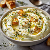 Une assiette de brandade de morue facile à préparer, avec des tranches de pain grillé et des herbes fraîches.