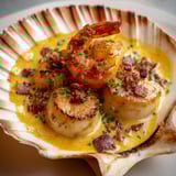 Une poêlée de Saint-Jacques lard et crème de safran, avec des herbes fraîches pour accompagner.