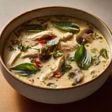 Une soupe thaïe parfumée au poulet, basilic et citron vert dans un bol en céramique.