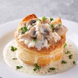 Une pâte croustillante et crémeuse, remplie de mushrooms et herbes, est servie sur un plateau.