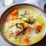 Un pot de Waterzoi de poulet avec des légumes et des carottes.