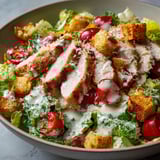 Une salade César à la noix de veau, composée de légumes frais et de tranches de viande, est servie dans un bol.