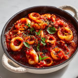 Une casserole de blancs d'encornets en sauce.