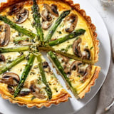 Une quiche aux asperges et aux champignons est servie sur un plateau.