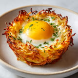 Œufs au four dans galettes de pommes de terre et carotte, recette rustique croustillante et fondante au fromage.