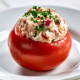 Un tomate farcié au thon sur un plateau blanc.