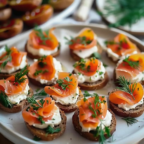 Assiette de canapés garnis de fromage à la crème et de tranches de saumon fumé, décorés de fines herbes.