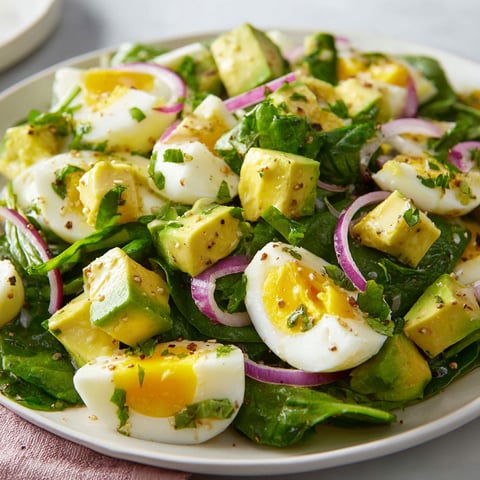 Une salade d'œufs à l'avocat et aux épinards est servie sur un plateau.