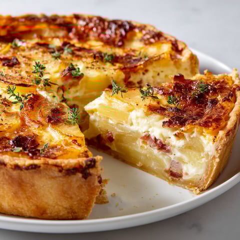 Une quiche façon tartiflette est servie sur un plateau.