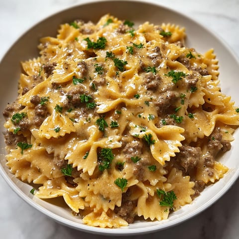 Un plat de pâtes papillon avec une sauce crémeuse et des viandes hachées.