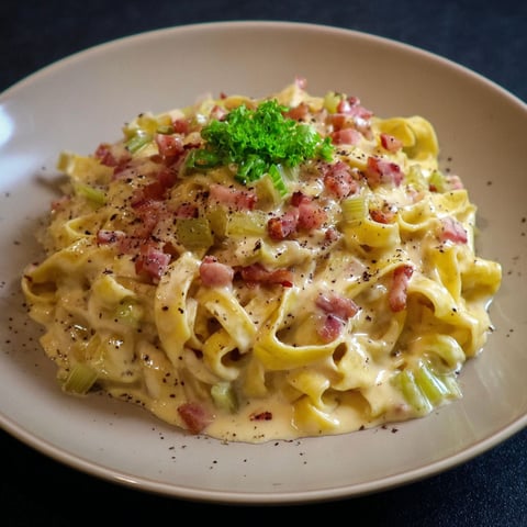 Une plate de tagliatelles à la carbonara de poireaux, servie sur un plateau.