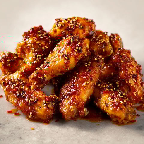 Les ailes de poulet miel, citron et sésame sont servies sur une table de marbre.