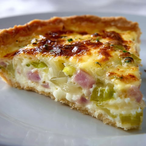 Une tarte légère aux poireaux et au jambon est servie sur un plateau.