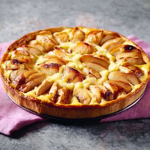 Une tarte normande aux pommes est servie sur un plateau.