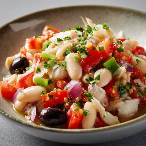 Une salade de tomates et d'olives, avec des herbes et des légumes, est servie dans un bol.