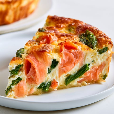 Une tranche de quiche sans pâte au saumon fumé et aux asperges.