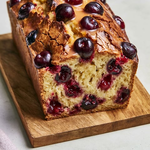 Une baguette de cake aux cerises et au kirsch, avec des cerises et du kirsch sur le dessus.