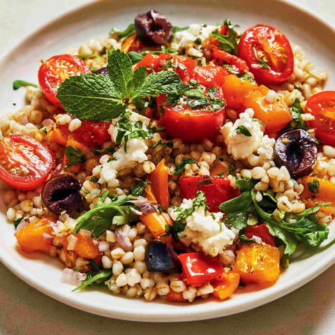 Une salade d'orge aux poivrons roti et a la feta, avec des tomates et des herbes