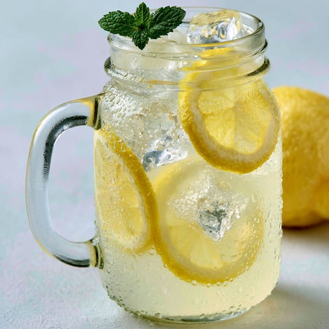 Une tasse de citronnade rapide, avec des citrons et des herbes, est prête à être consommée.