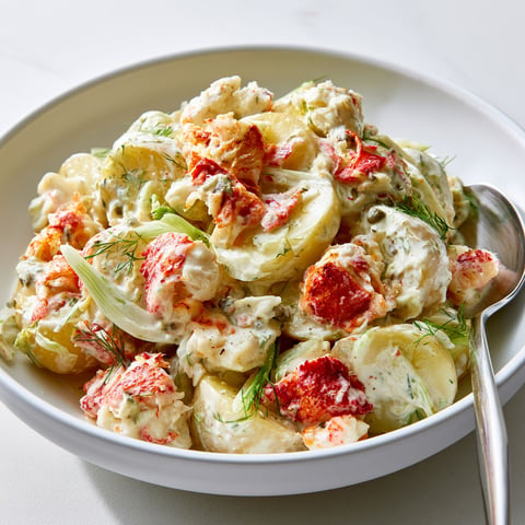 Une salade de pommes de terre au crabe est servie dans un bol en porcelaine.