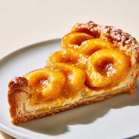 Une tarte aux mirabelles au rhum est servie sur un plateau.